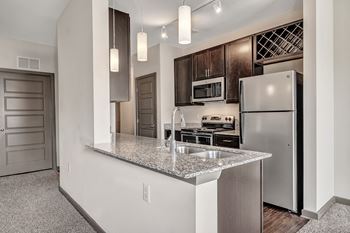 A kitchen with a granite countertop and stainless steel appliances.